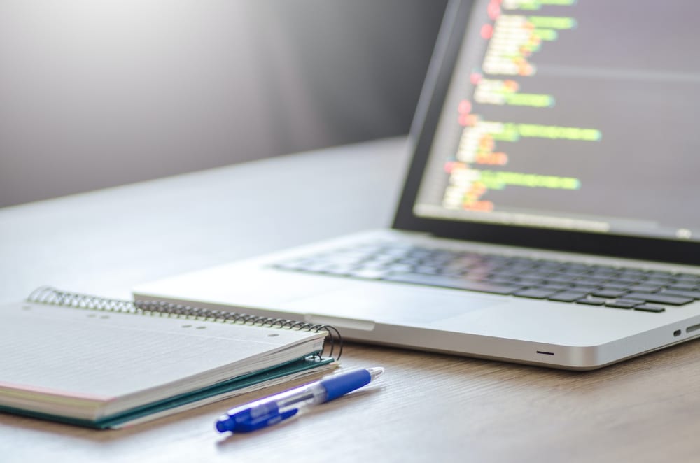 Een laptop staat open met daarop een rij HTML code weergegeven