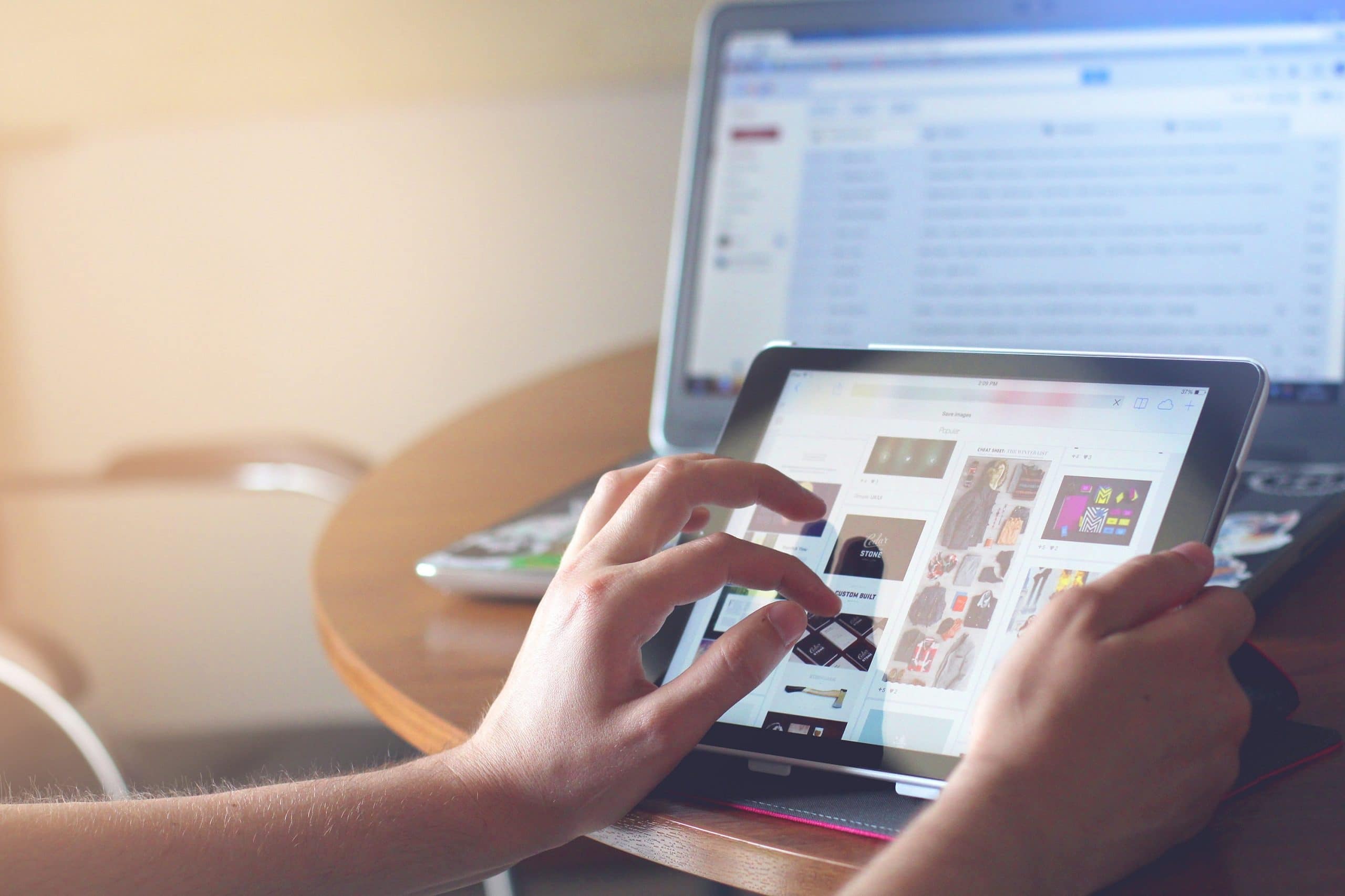persoon met ipad en pc voor zich