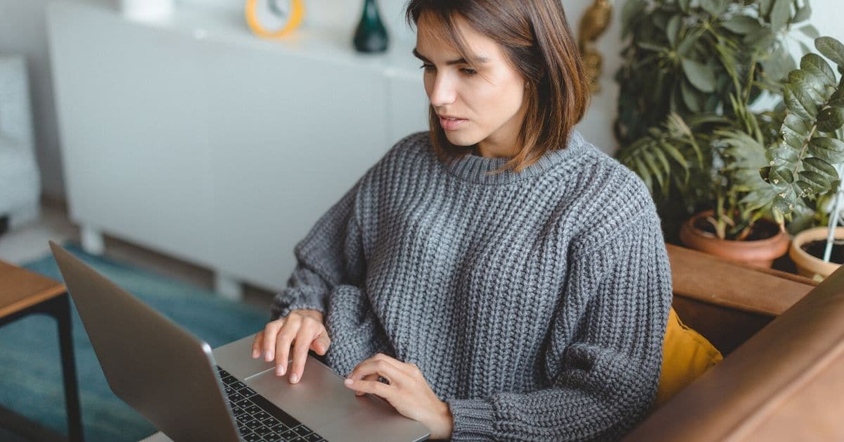 Een vrouw die op haar laptop thuis aan het werk is