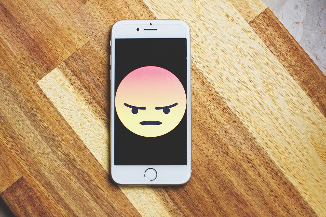 telefoon op een tafel met een boze emoji
