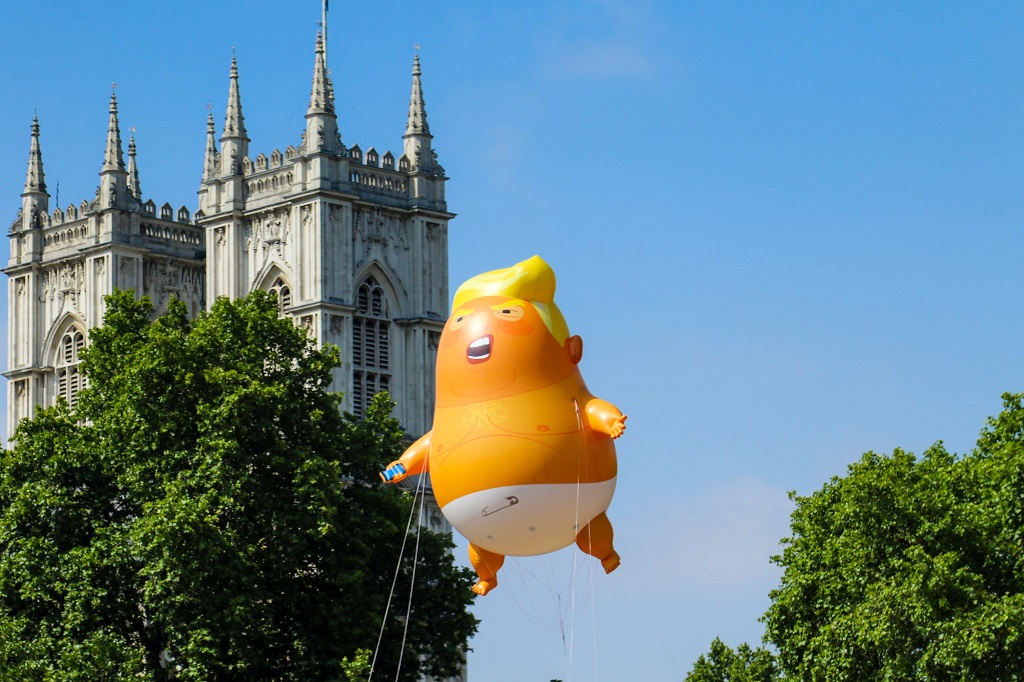 Boven Londen zweeft een ballon aan een touwtje die Trump uitbeeldt als een klein kindje in een luier