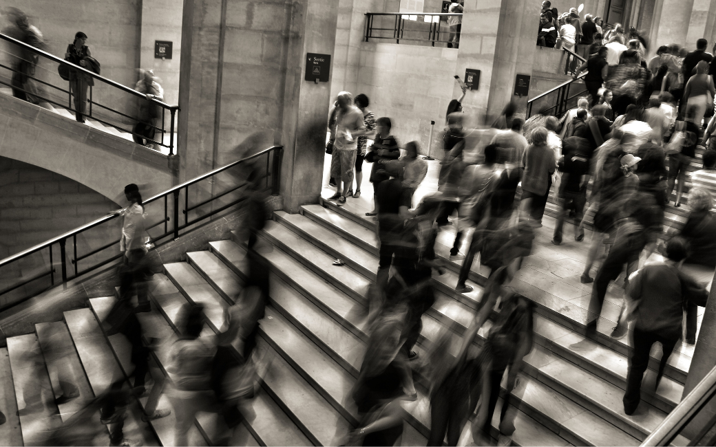 Een druk treinstation in zwart-wit met voorbijsnellende mensen op trappen