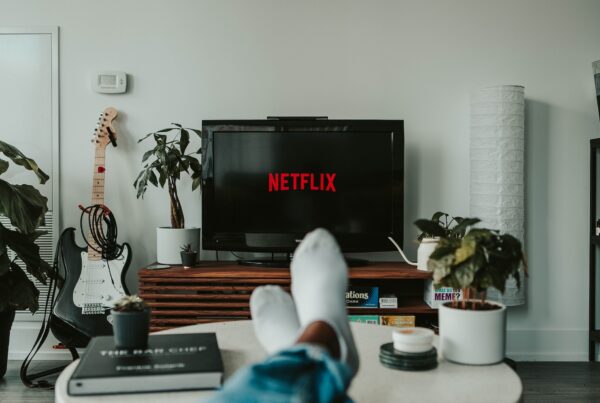Gezien vanaf iemand op de bank die met zijn sokken op de koffietafel ligt en kijkt naar een televisie met daarop het Netflix logo