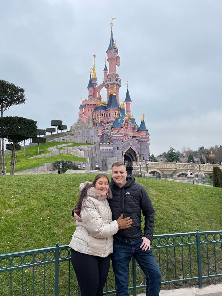 Charissa en haar vriend poseren voor het roze kasteel in Disneyland.