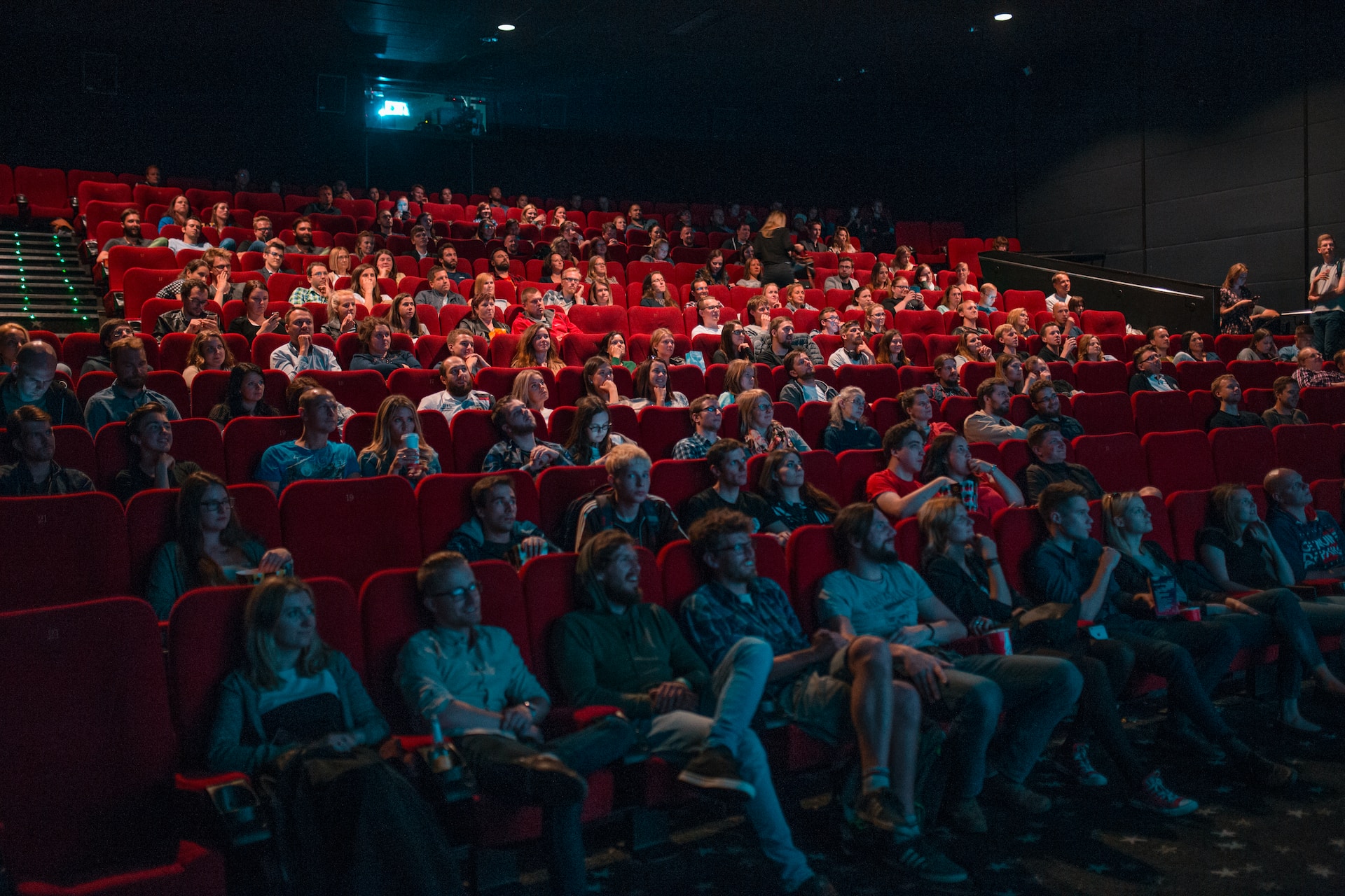Een bioscoopzaal met rode stoelen vol mensen
