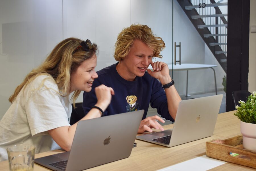 steffi en menno zitten in een overlegruimte en kijken lachend naar de laptop van menno