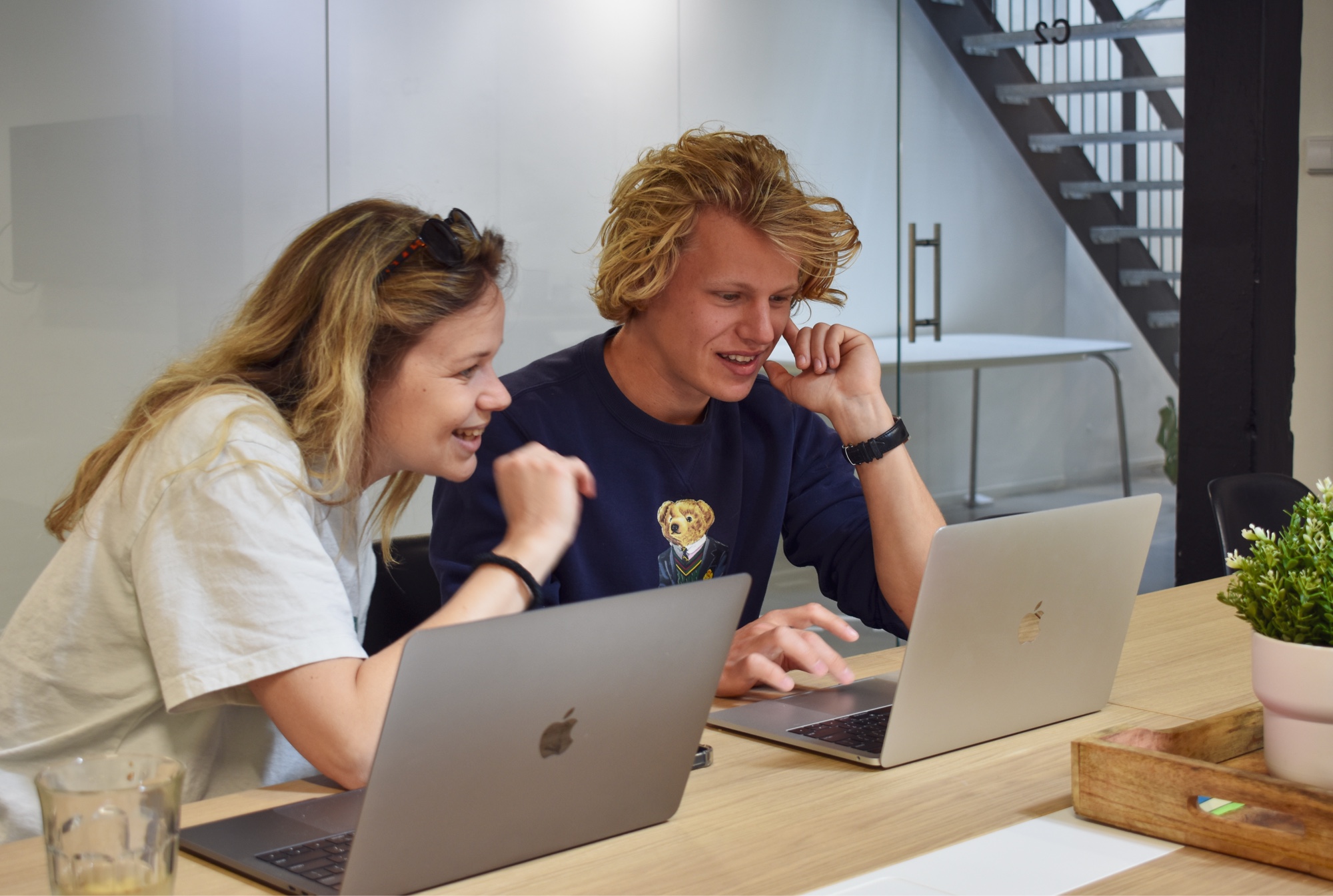 steffi en menno zitten in een overlegruimte en kijken lachend naar de laptop van menno