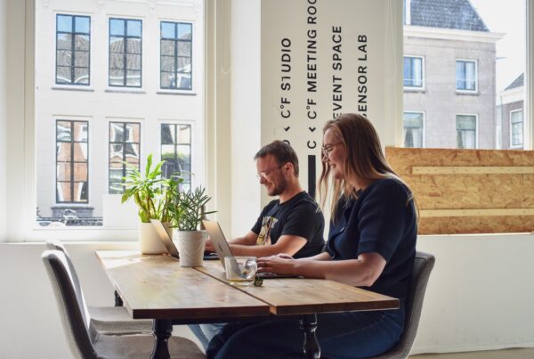 Pim en Emma zitten bij het raam aan de plompetorengracht en lachen beiden