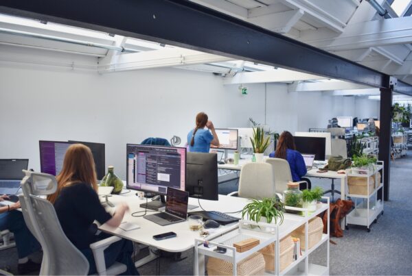 het kantoor van digitaal toegankelijk, met mensen die aan het werk zijn achter schermen. De ruimte is lang en licht met veel planten