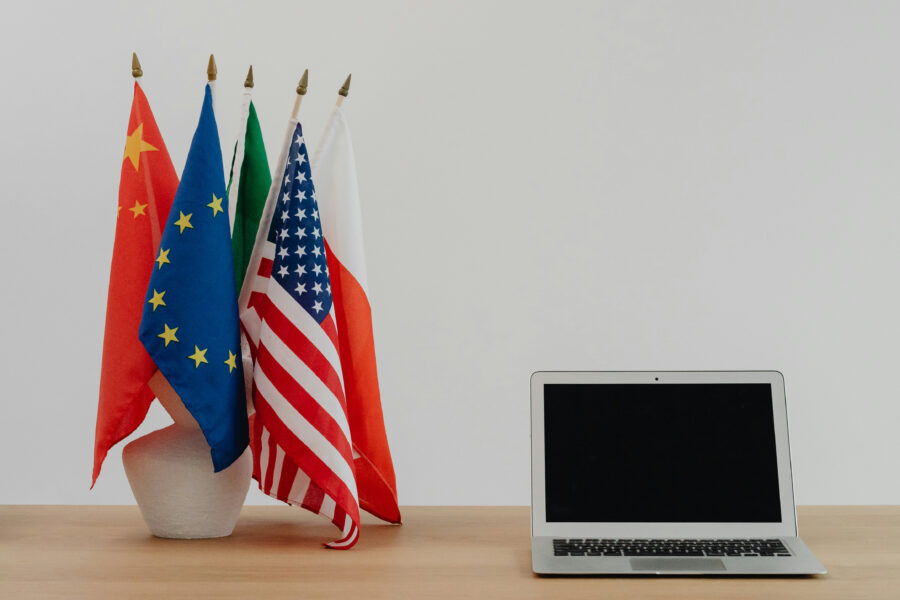 kleine vlaggetjes van Europa, de VS en andere landen staan in een vaasje naast een laptop